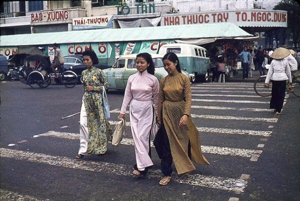  Những người phụ nữ mặc áo dài thong thả trên đường phố Sài Gòn.
