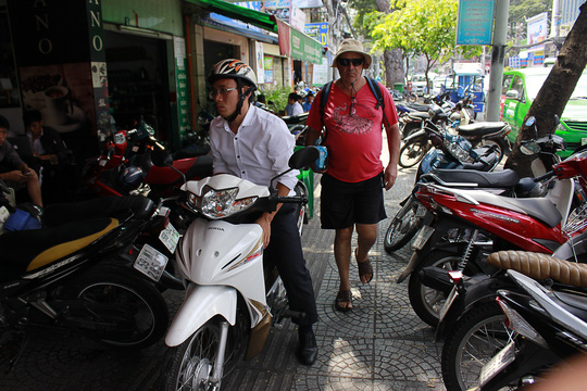 Một du khách nước ngoài di chuyển khó khăn trên đường Nguyễn Thị Minh Khai (quận 1) vì vỉa hè bị chiếm dụng.