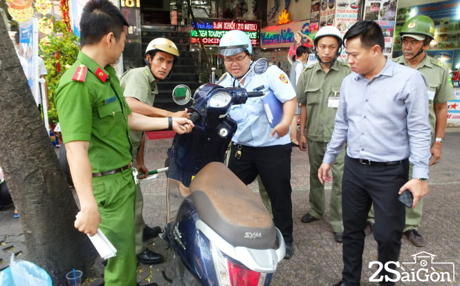 Lực lượng chức năng tạm giữ một xe máy không người nhận đậu trên vỉa hè đường Phạm Ngũ Lão - Ảnh: Lê Phan 