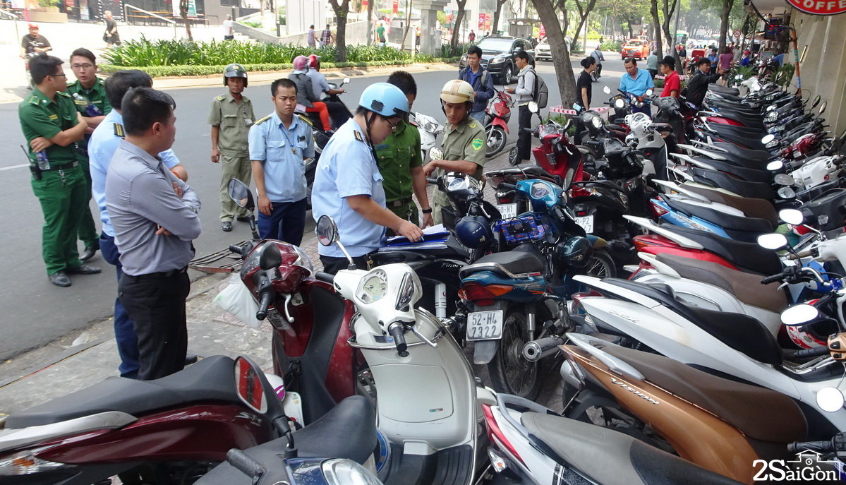 Lực lượng chức năng lập biên bản xử phạt một cửa hàng cho xe máy của khách đậu tràn ra vỉa hè - Ảnh: Lê Phan 