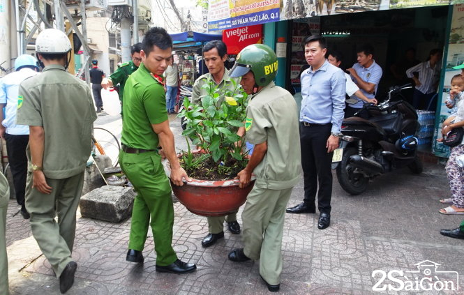Lực lượng chức năng thu giữ các chậu hoa đề tràn ra vỉa hè đường Phạm Ngũ Lão - Ảnh: Lê Phan 